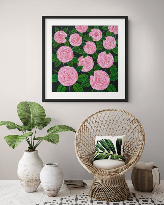 Éclat des Roses fine art print by Nelleke Bruno displayed above a chair with a green plant in a stylish interior, bringing vibrant floral colour and timeless elegance.